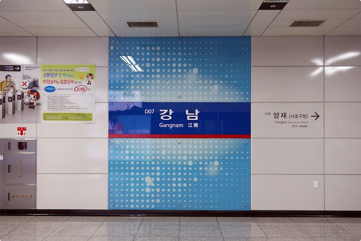 地下鉄の江南駅の案内表示が壁面に大きく掲示された駅構内の様子です。