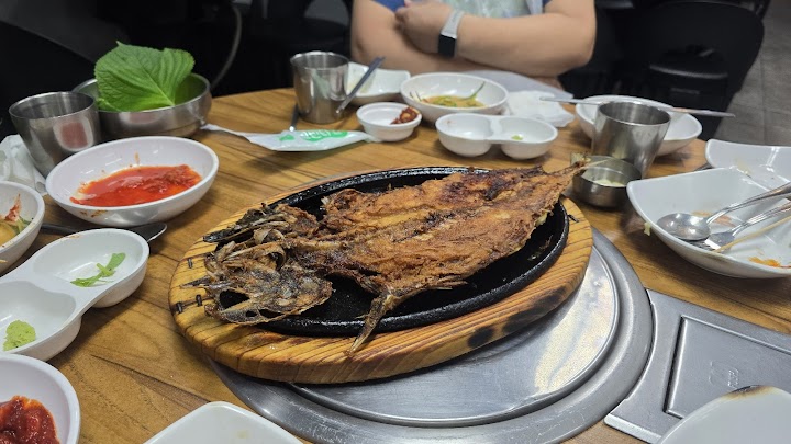 乙支路の路地裏にある老舗食堂で、香ばしく焼かれた焼き魚定食を。並べられた小さなおかずや金属製の器が、韓国の日常を感じさせてくれます。