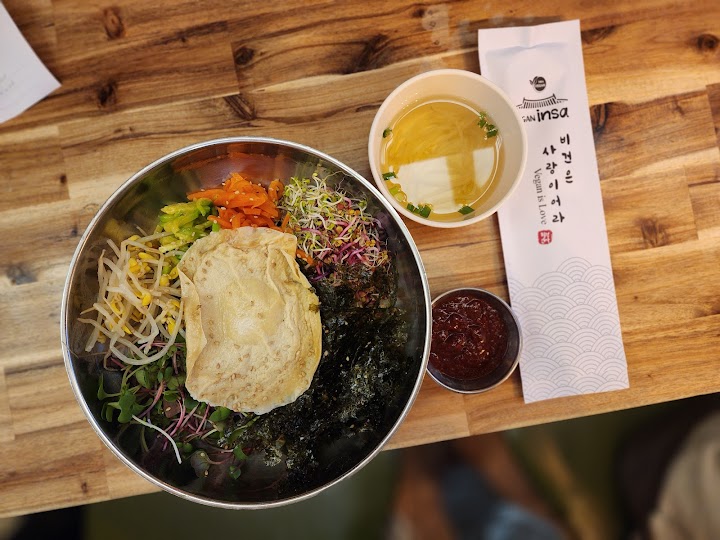 仁寺洞の路地裏で見つけたビーガン店で、野菜たっぷりのビビンバランチ。歩き疲れた体に優しい味と、一人でも落ち着ける木のテーブルが嬉しい。