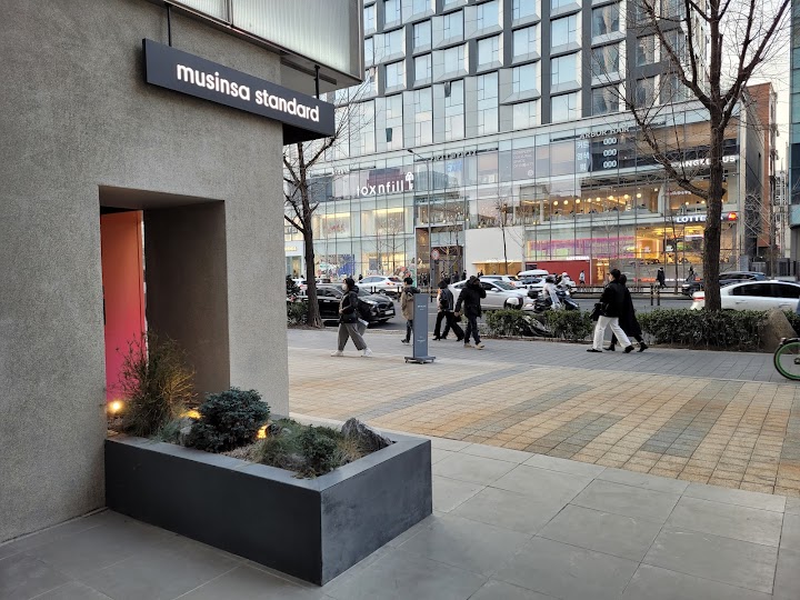 弘大の街並みに溶け込むムシンサスタンダードの店舗外観。行き交う人々や向かいのビルも見えて、活気あるエリアの雰囲気が伝わってきます。