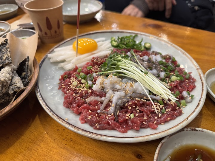 広蔵市場のユッケ通りで出会った、新鮮な生肉と活タコのコリコリ感がたまらない絶品グルメです。