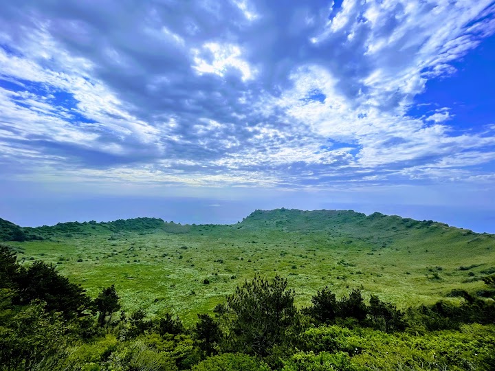 城山日出峰の山頂に到着！目の前に広がる巨大で緑豊かな噴火口の絶景に、登山の疲れも吹き飛びました。
