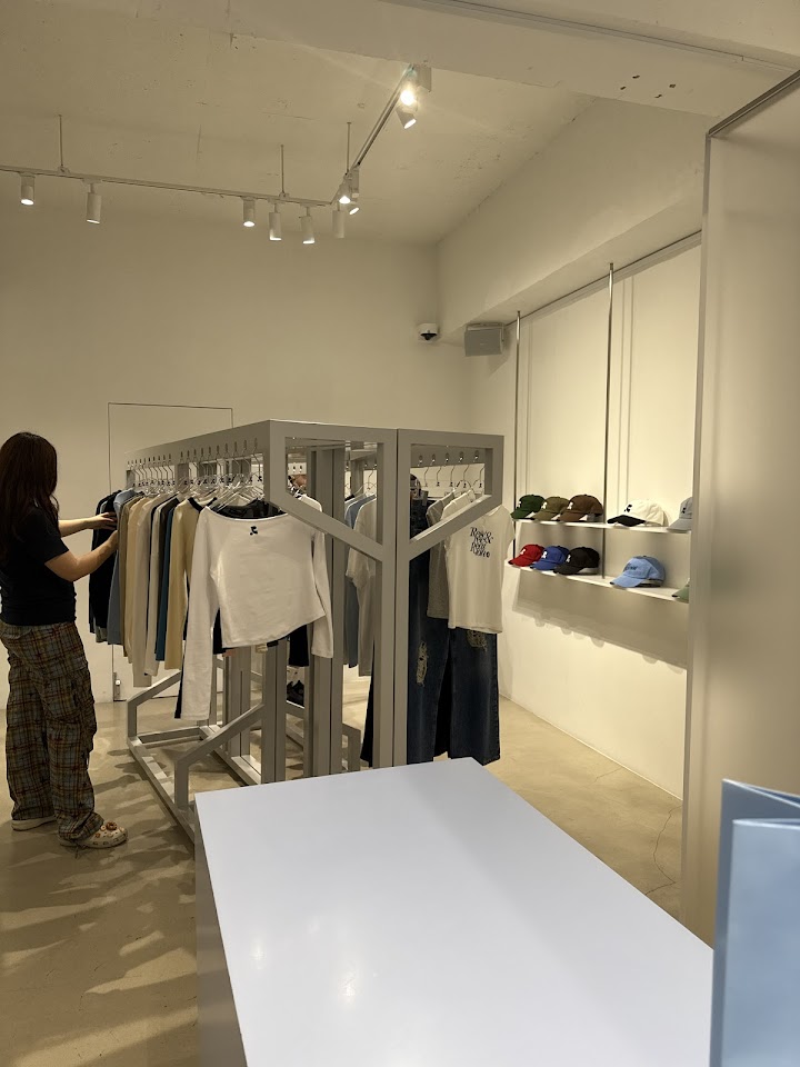 漢南洞のレストアンドレクリエーションのショールームで、実際にハンガーにかかった服を手に取って素材感を確かめている様子。
